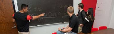 ר students solving a math equation on a blackboard